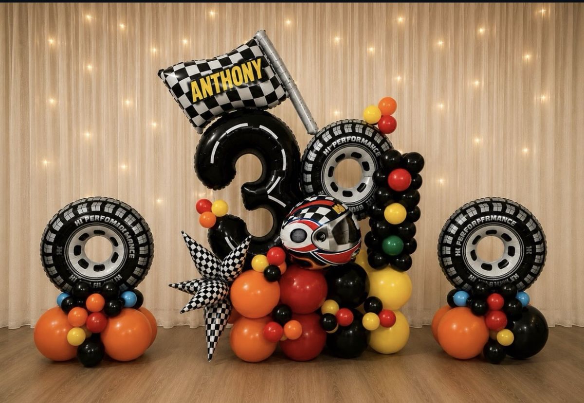 Race-themed balloon marquee with a black number 30, tire balloons, a checkered flag reading Anthony and a helmet balloon