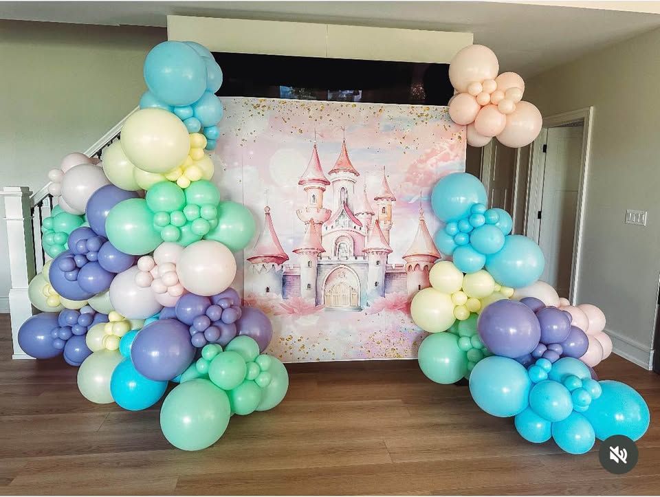 Pastel mint, lavender, peach, blue and cream balloon garlands framing a watercolor castle backdrop